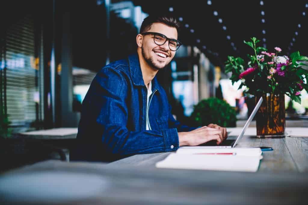 A smiling man working on a laptop