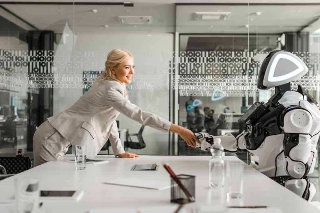 Woman shaking hands with a robot as if in a job interview