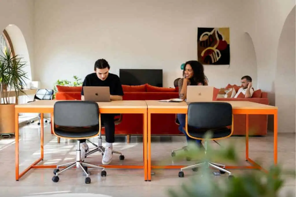 A large table with two people working on laptops in a bright, airy room.