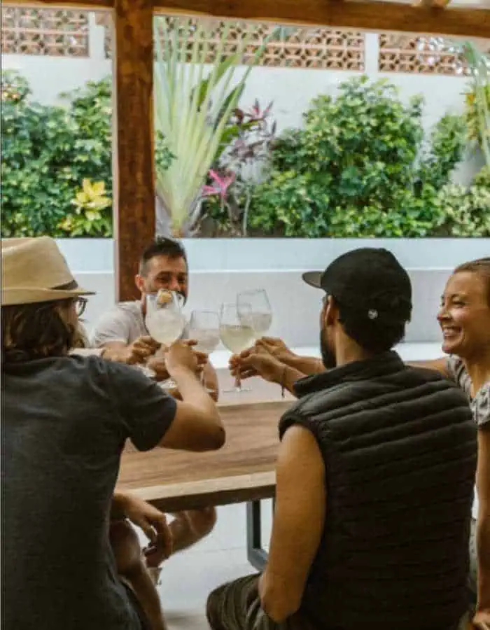 People gathered around a table on a patio. There are trees in the background.