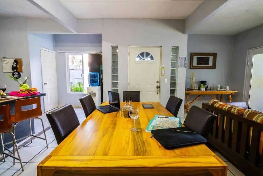 A long table with two laptops on top. You can see part of the kitchen and part of a living room.
