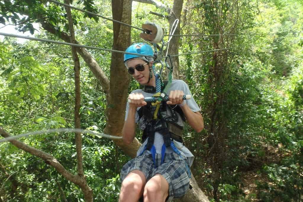 Young man ziplining among the trees