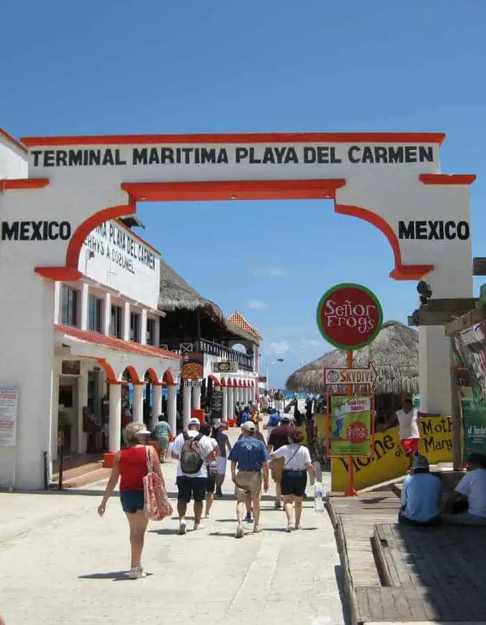ChatGPT said:
Tourists walk under the white and red archway entrance of the Terminal Marítima Playa del Carmen. Shops, signs, and beachside buildings line the pathway toward the ocean under a bright blue sky.