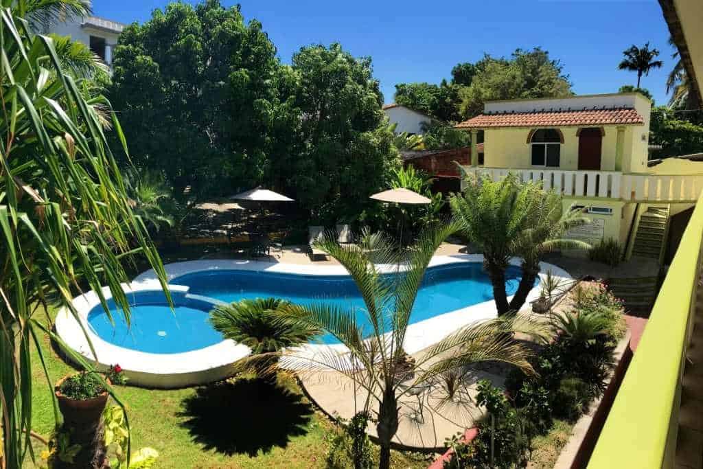 A beautiful resort-style swimming pool surrounded by grass and palm trees.