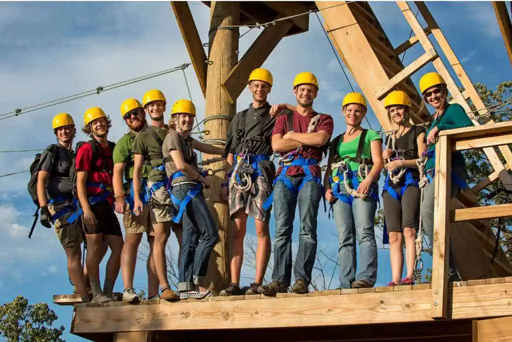 Group of people on a zipline platform in their harnesses.