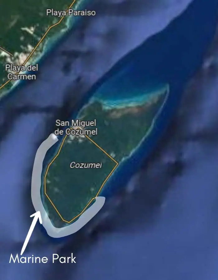 The image is a map highlighting Cozumel Island, located off the coast of Playa del Carmen, Mexico. A white outline marks the Marine Park on the island’s southwestern side, with major locations such as San Miguel de Cozumel labeled. The surrounding turquoise waters and reefs are visible.