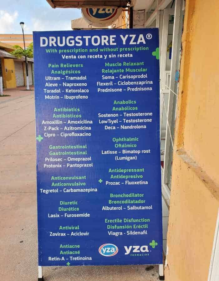 A blue signboard for 'DRUGSTORE YZA' lists available medications categorized into pain relievers, muscle relaxants, antibiotics, and more, indicating availability with and without prescription. The sign is prominently displayed on a peach-colored wall.
