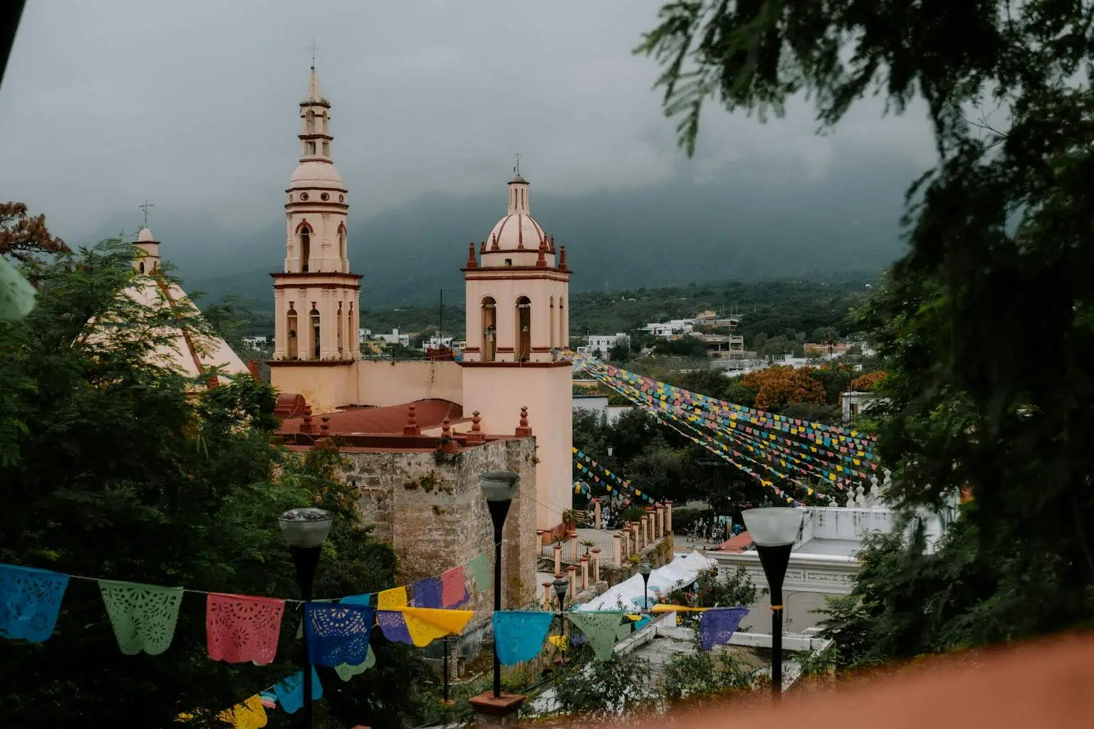 View of a vibrant church in Monterrey, Mexico decorated with festive bunting, set against a mountainous backdrop.